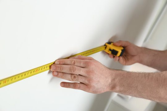 How to build a fitted wardrobe: measuring wardrobe space accurately with tape measure and level for perfect fit.