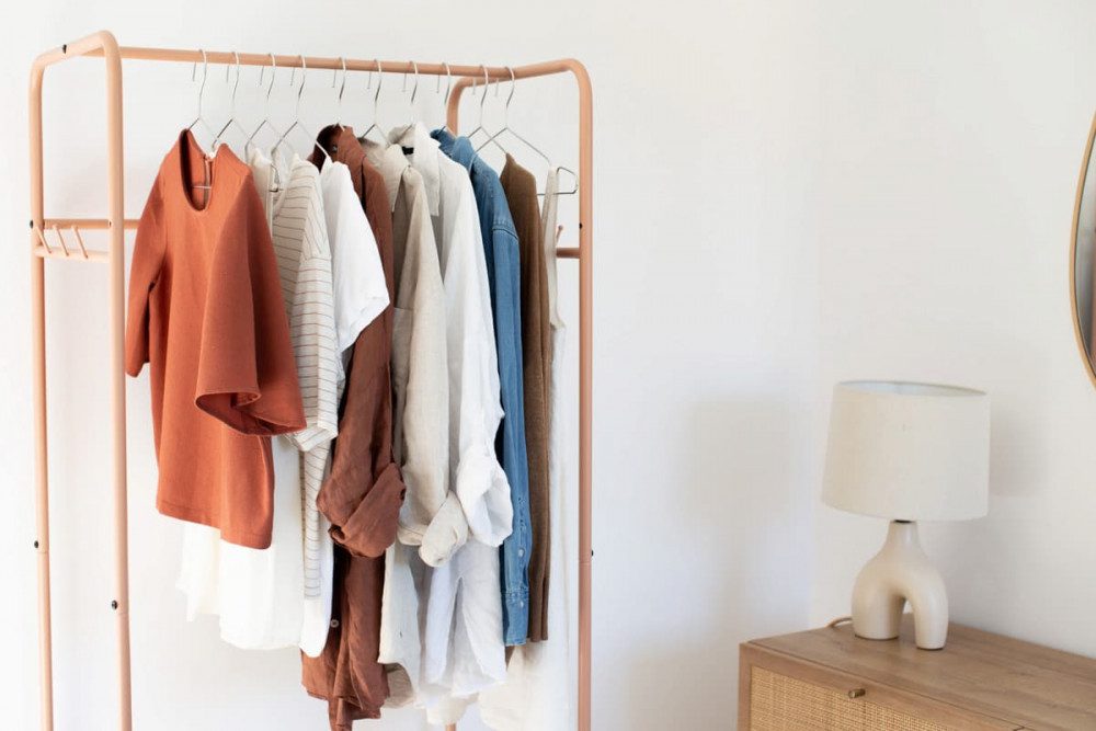 Leran how to create a minimalist wardrobe well-organised with neatly arranged shirts on a simple clothing rail.